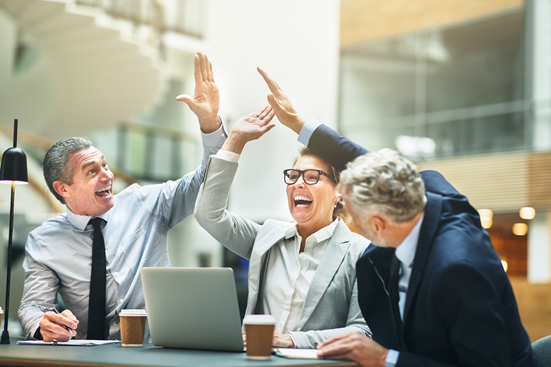 Ecstatic group of colleagues gathering at a meeting around a table in the lobby of an office building