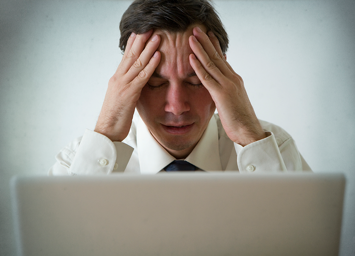 Man sitting at laptop, looking stressed
