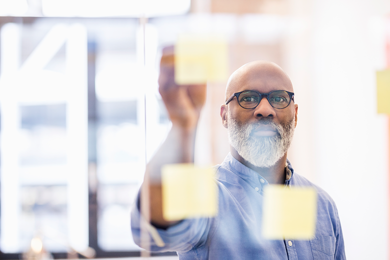 Shot of a businessman plotting out a plan with markers on a glass wall in his office