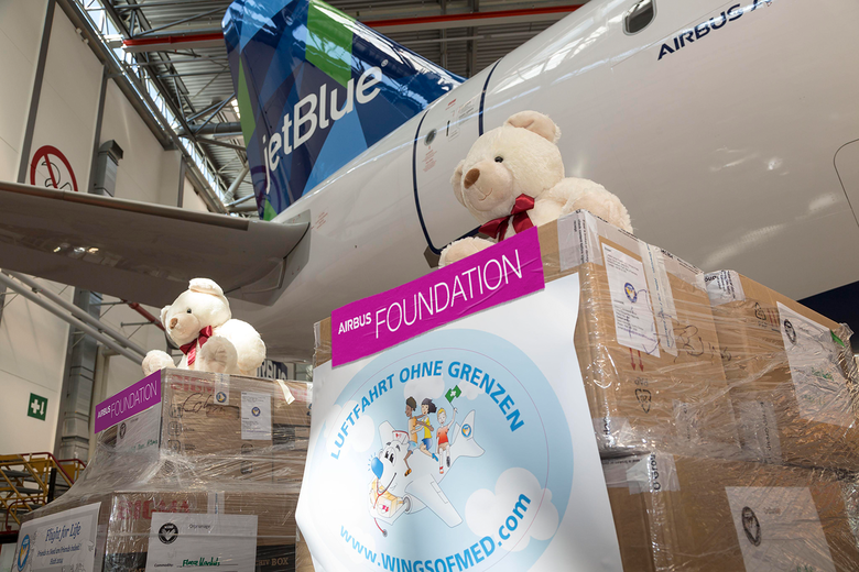 Airbus Foundation stickers on packages with teddy bears in front of a jetBlue aircraft